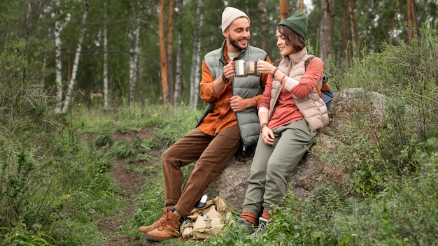 Full shot happy couple enjoying hot drink in nature