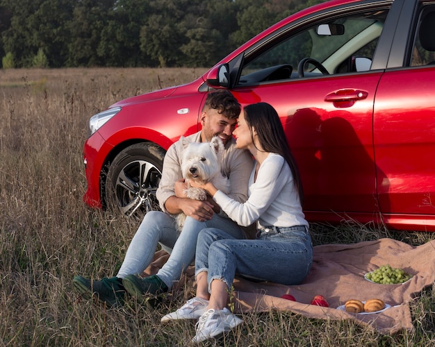 Free photo full shot happy couple on grass with dog