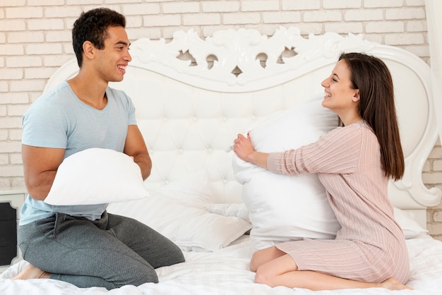 Full shot happy couple holding pillows