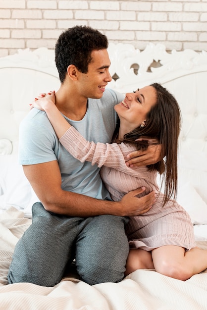 Full shot happy couple hugging in the bedroom