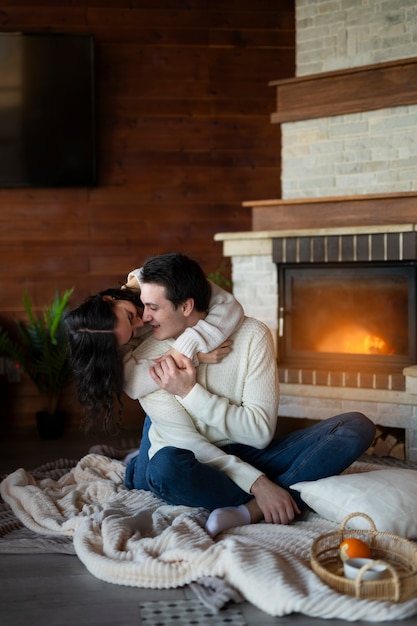 Full shot happy couple hugging by the fire