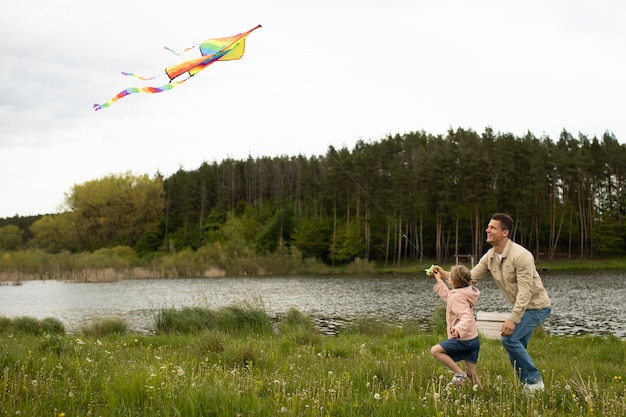 Полный снимок счастливая семья запускает воздушный змей на природе