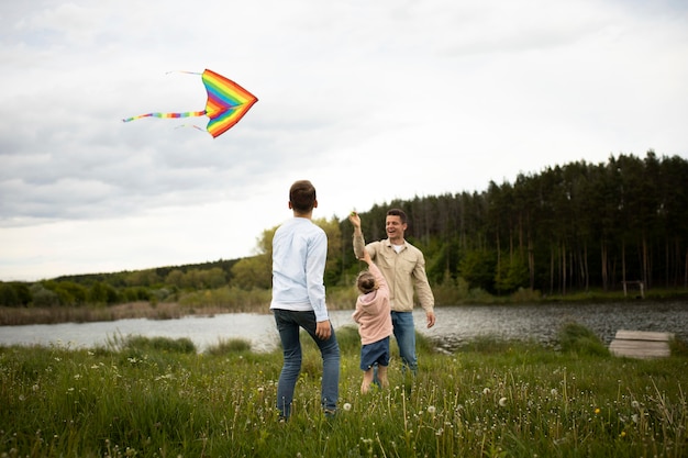 Free photo full shot happy family flying kite outdoors