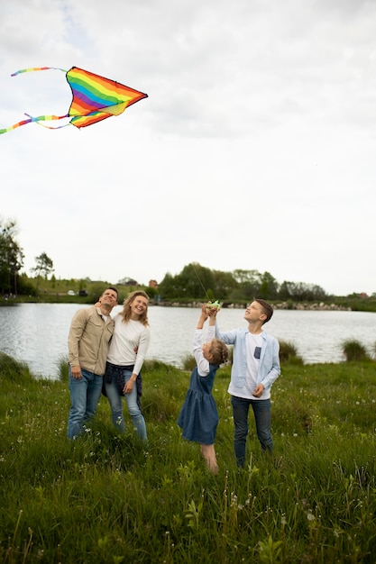 Foto gratuita full shot famiglia felice che vola aquilone arcobaleno