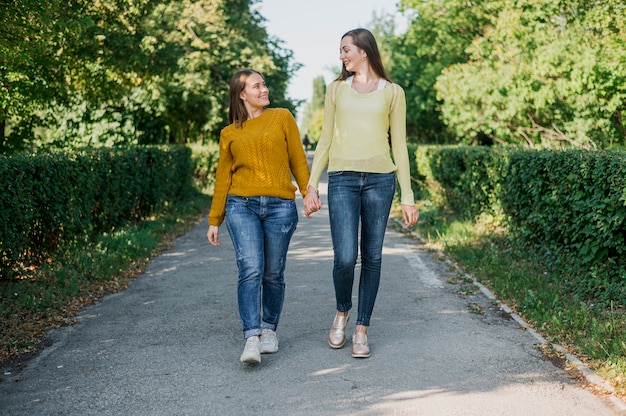 Full shot happy friends holding hands outdoors