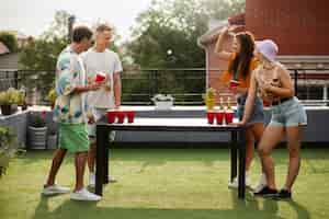 Foto gratuita amici felici del colpo pieno che giocano a beer pong