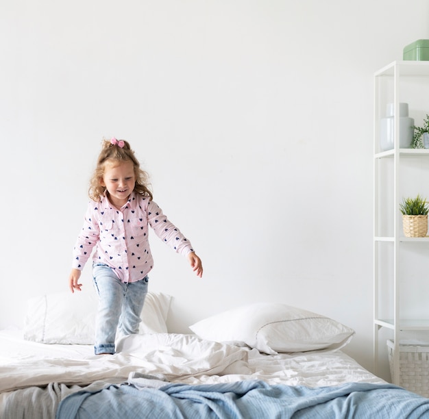 Ragazza felice della foto a figura intera che cammina sul letto