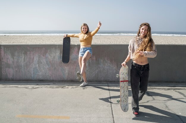 Full shot happy girls with skateboard