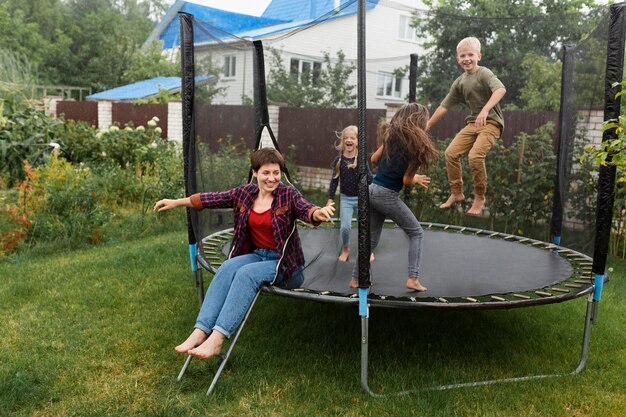 Full shot happy kids jumping on trampoline