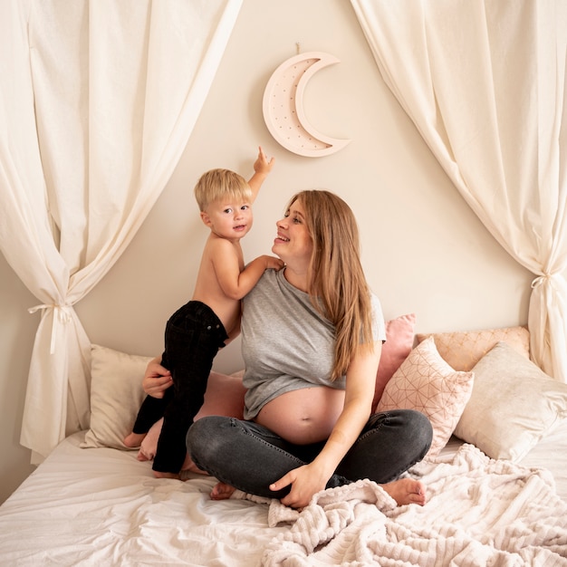 Full shot happy mother with son in bed