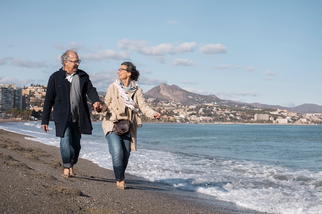 해변을 걷는 전체 샷 행복한 노인들