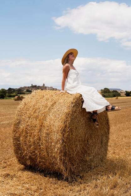 Полный снимок счастливая женщина, сидящая на сене