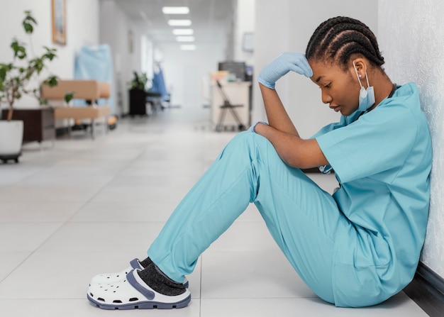 Full shot health worker sitting on floor