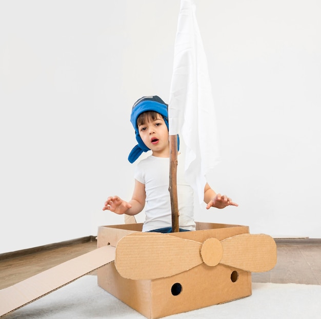 Full shot kid in cardboard boat