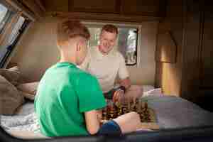 Free photo full shot kid and father playing chess