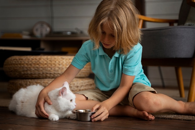 フルショットの子供が猫に餌をやる