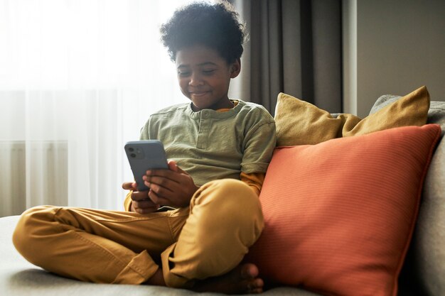 Full shot kid holding smartphone