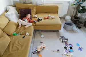 Free photo full shot kid laying on couch with toys