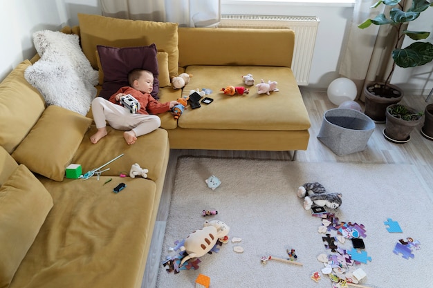 Full shot kid laying on couch with toys