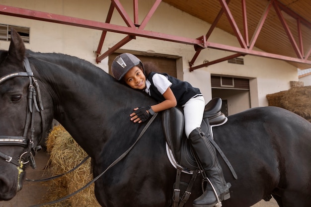 Foto gratuita ragazzo a tutto campo che impara a cavalcare