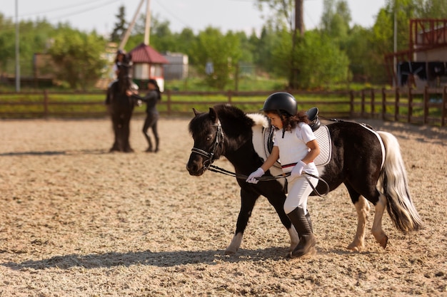 Бесплатное фото Полный кадр ребенок учится кататься на лошади