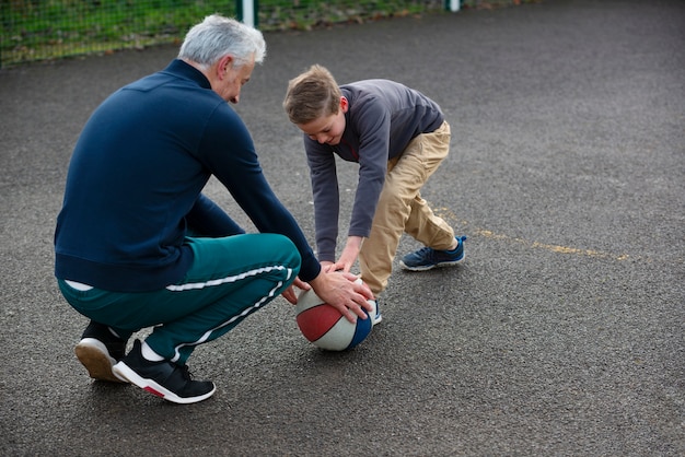 Full shot kid and man with ball