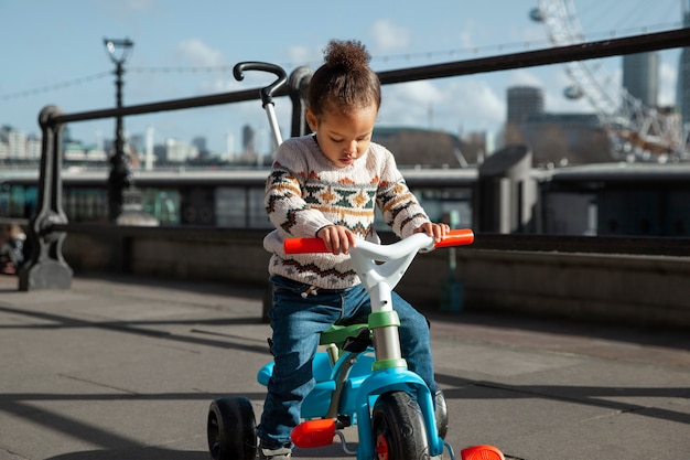 Бесплатное фото Полный снимок ребенка на трехколесном велосипеде снаружи