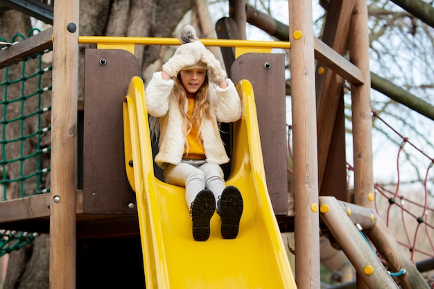 Full shot kid playing on slide