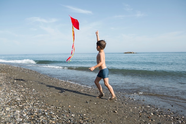 Free photo full shot kid playing with kite