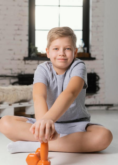 Full shot kid posing with dumbbells