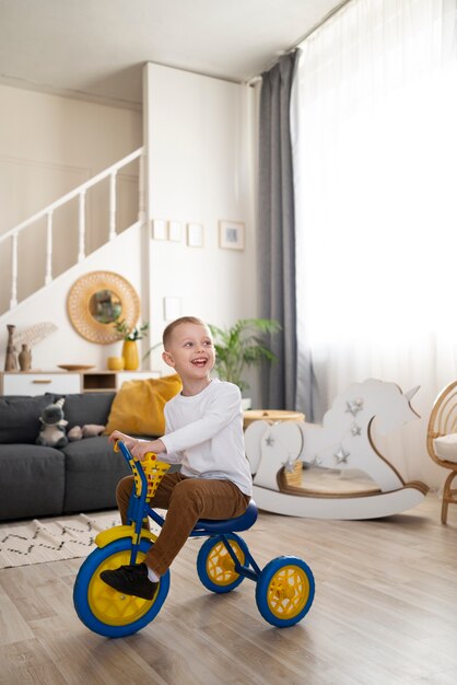 Full shot kid riding tricycle at home