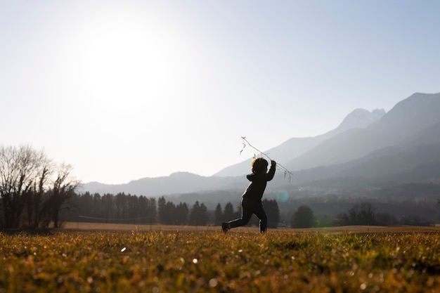 Foto gratuita siluetta del bambino del colpo pieno che corre in natura