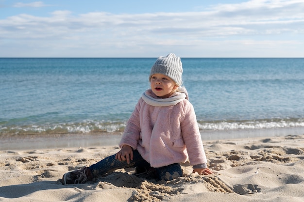 Foto gratuita ragazzo a tutto campo seduto sulla spiaggia