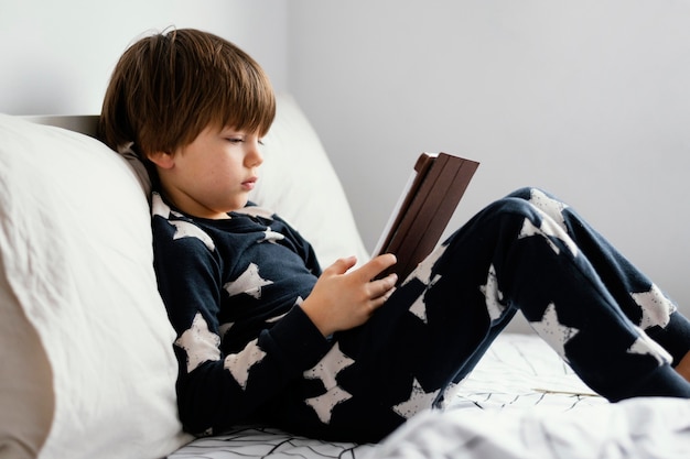 Full shot kid sitting in bed