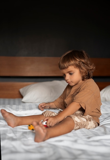 Full shot kid sitting in bed