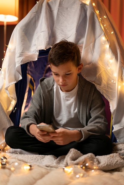 Full shot kid sitting with smartphone