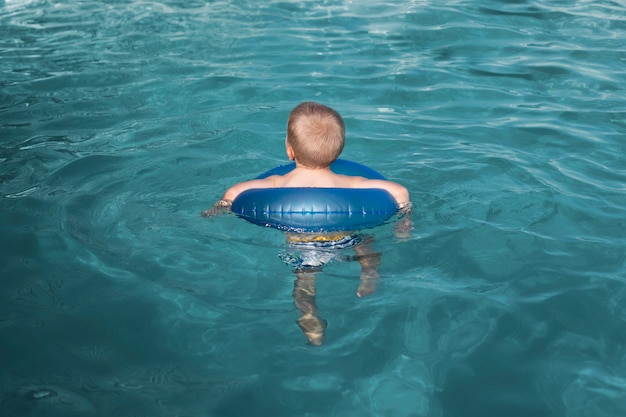 Full shot kid swimming with lifebuoy