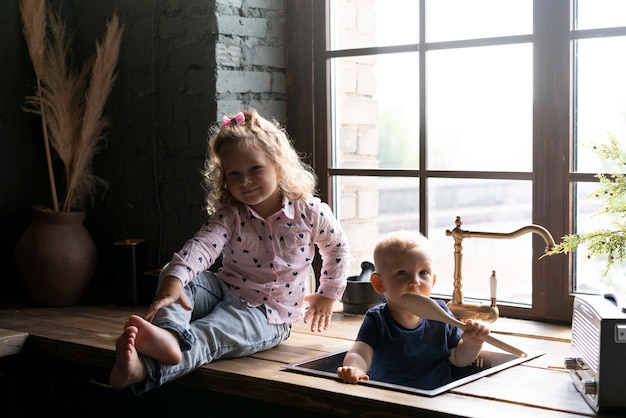 Full shot kid with baby sitting in the sink