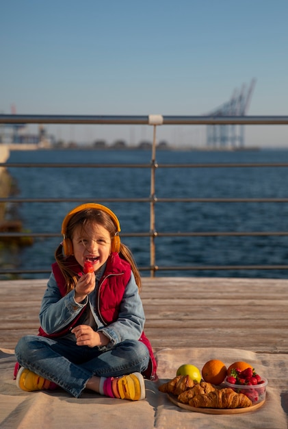 Free photo full shot kid with food on a jetty