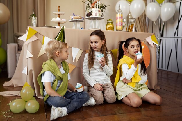 Full shot kids eating cupcakes