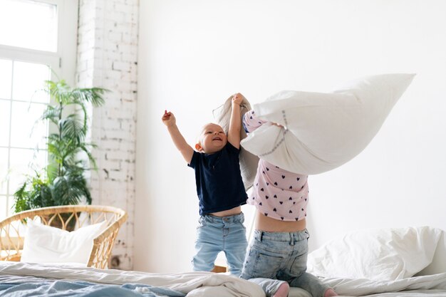 Full shot kids fighting with pillows