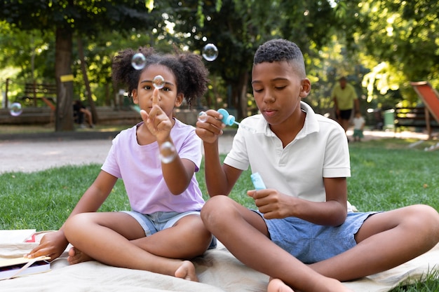 Foto gratuita bambini a tutto campo che fanno bolle di sapone