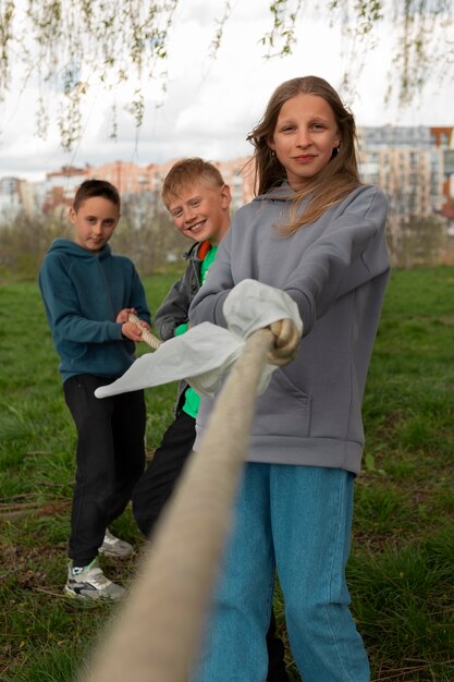 Full shot kids playing tug-of-war in the park