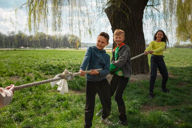 Full shot kids playing tug-of-war in the park