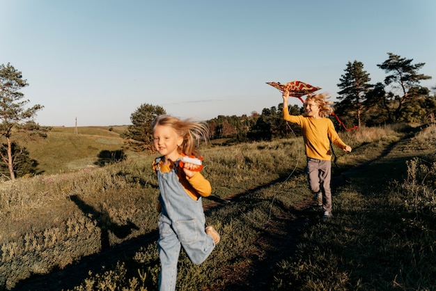 Free photo full shot kids playing with kite