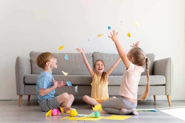 full shot kids playing with paper