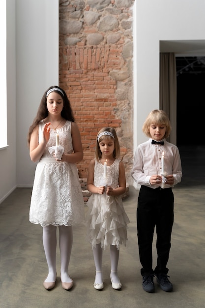 Full shot kids praying with candles