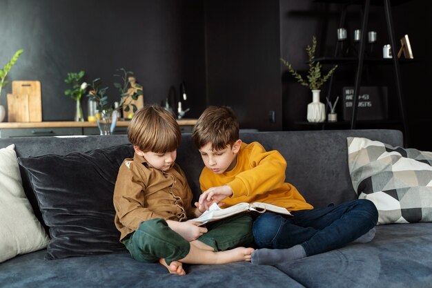 Full shot kids reading bible on couch
