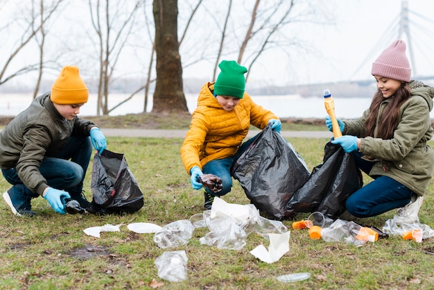 Free photo full shot of kids recycling on ground