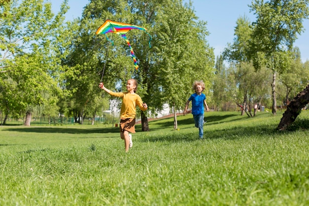 Free photo full shot kids running with kite